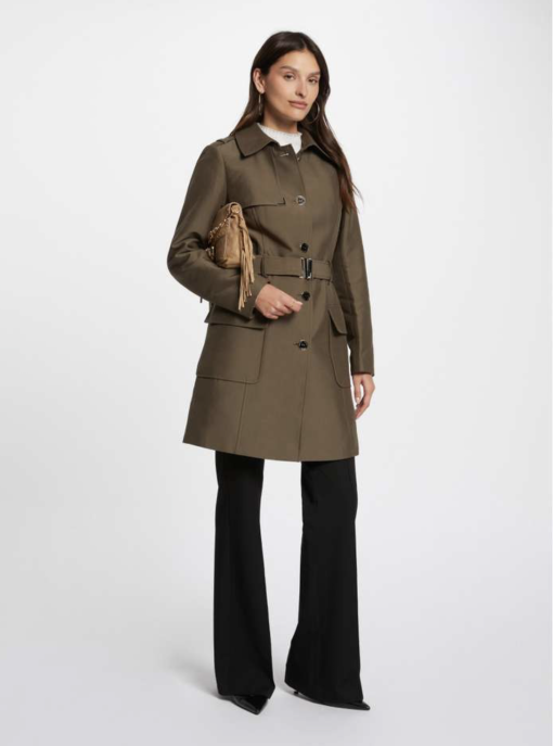 trenchcoat groen klassiek model, Deze super leuke trenchcoat valt mooi ruim over de knieën maar wel met een pittige snit....strak silhouet met een mooie afwerking op de schouders van kleine zilveren ringetjes welke door de stof zijn geponst, leuke gespen op de mouwen voor net even wat meer allure. Deze trenchcoat heeft door het gebruik van een mooie luxe stof (katoen/strech) met een lichte subtiele glans een hele luxueuze look! Dit is wat we noemen een door draag model, voor nu in de herfst helemaal leuk maar ook in het naseizoen en in de killere herfstdagen goed te combineren met een lekker dikke coltrui eronder. Morgan de toi is een frans label, dit betekend alles net even iets strakker.Dit model valt strak op de schouders om de mooie pittige lijn te krijgen, maar mocht je wat meer ruimte willen dan 1 maatje groter bestellen.